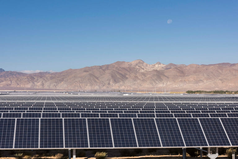 Photo of a large solar plant in front of mountains